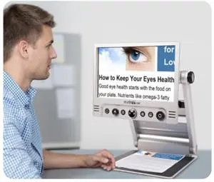 A man sitting in front of an electronice device with a screen magnifying the words from a printed page.